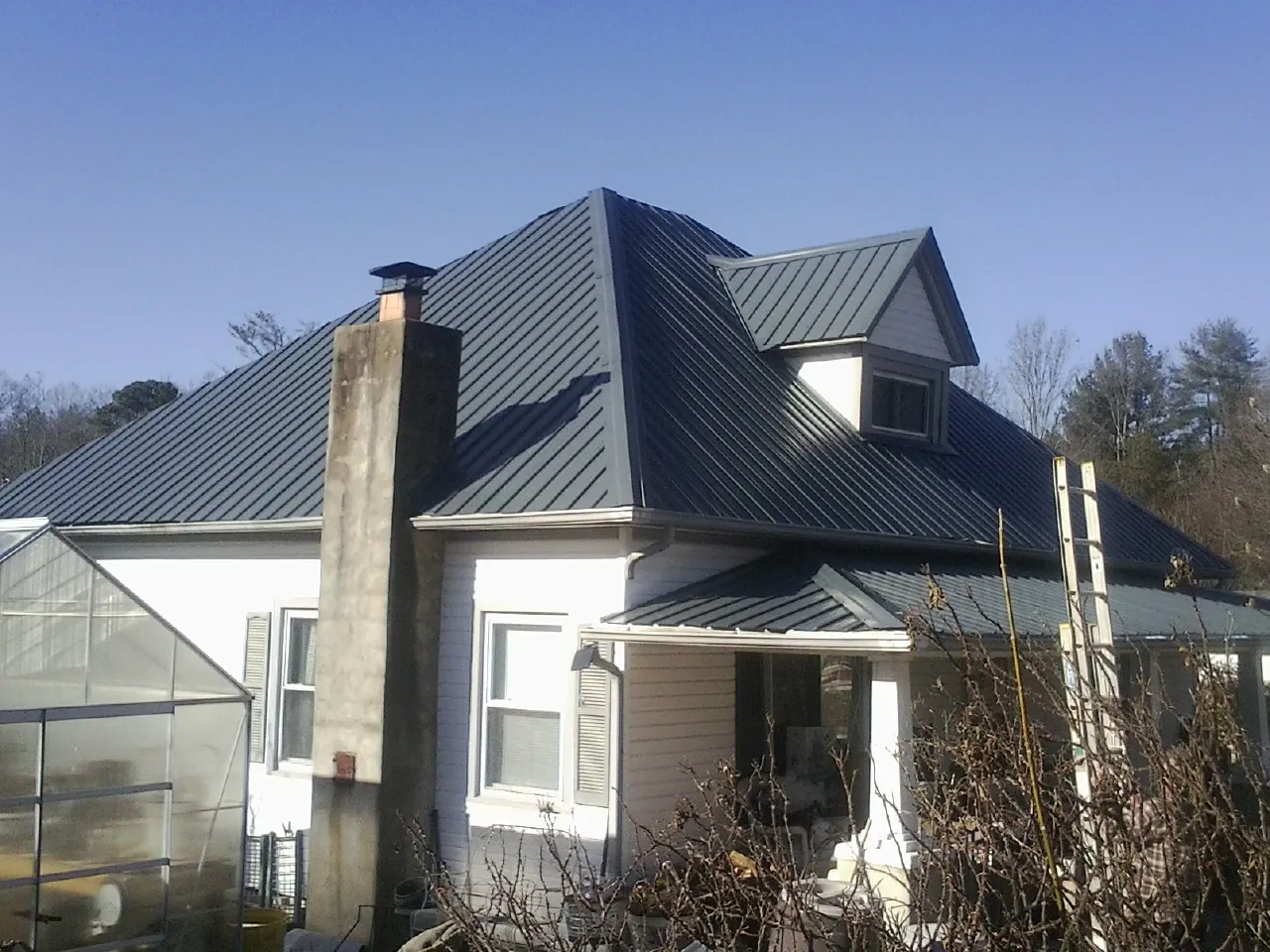 Dark blue standing seam metal roof on a white farmhouse with dormer — Slate & Tile Roof Repair by Roofing Brothers in Basalt