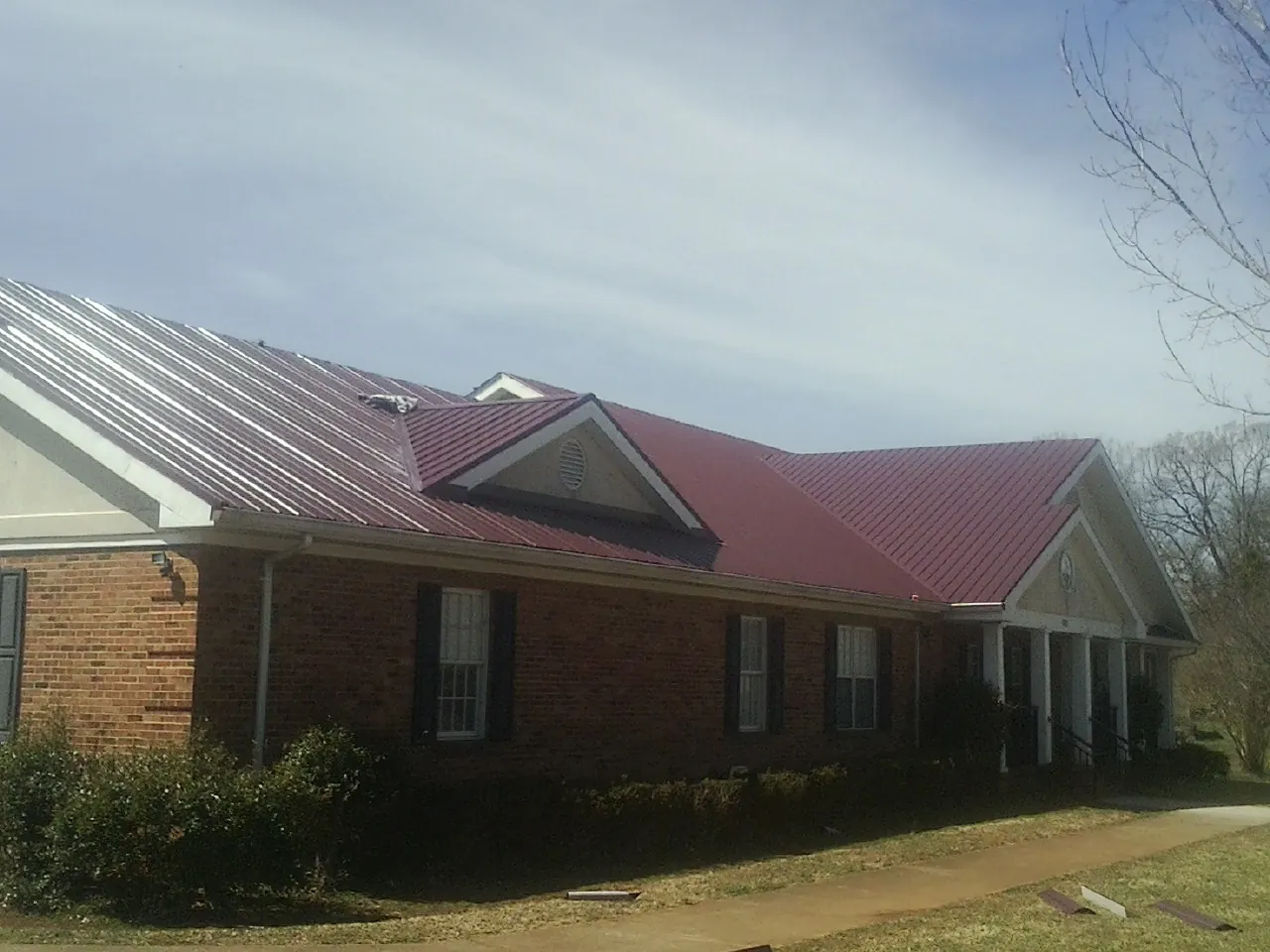 Red metal roof with gabled entries on a long brick building, from a Hail Damage Roof Repair job in Basalt