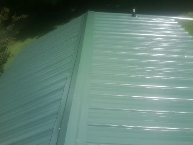 New green metal panels meeting at the ridge of a roof — Flat Roof Repair work by our crew in Basalt