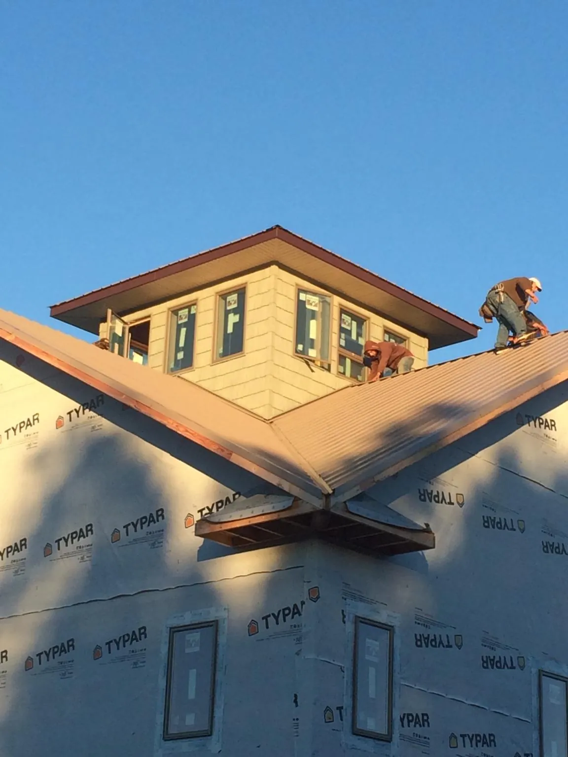 Roofers working around a rooftop cupola on a new metal roof at sunset — Roof Waterproofing in Basalt by Roofing Brothers